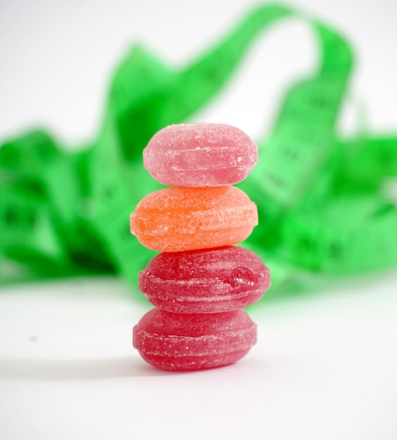 bonbons durs aux fruits colorés et ruban à mesurer isolés sur le concept de régime blanc