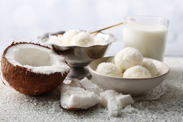 Bonbons faits maison en flocons de noix de coco et noix de coco fraîche sur fond clair