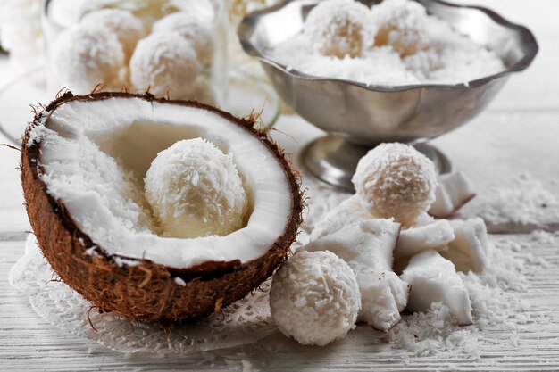 Bonbons faits maison en flocons de noix de coco et noix de coco fraîche sur fond clair