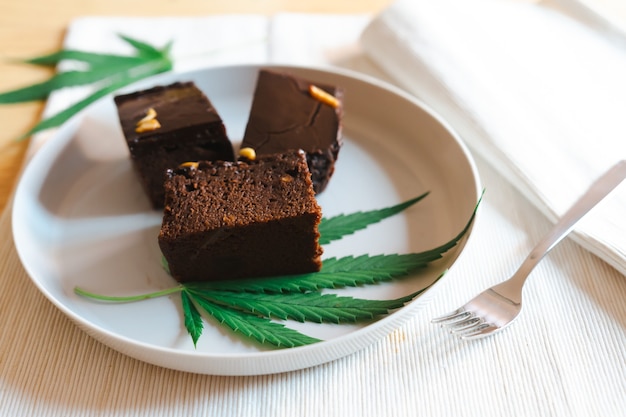 Bonbons faits maison avec de la marijuana ou des feuilles de cannabis sur une plaque blanche. Concept de médecine alternative.