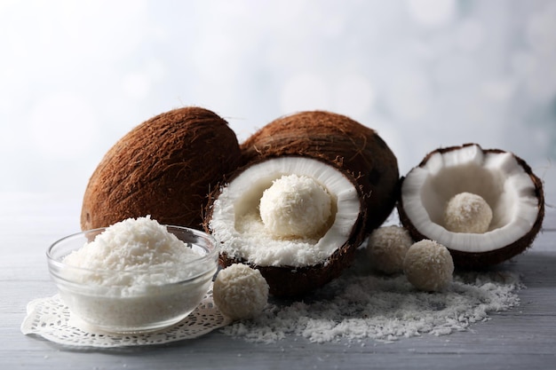 Bonbons en flocons de noix de coco et noix de coco fraîche sur fond de bois de couleur