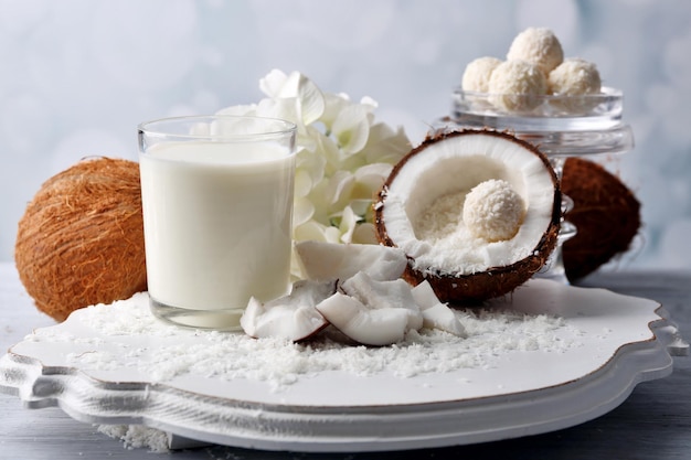 Bonbons en flocons de noix de coco et noix de coco fraîche sur table en bois de couleur, sur fond clair