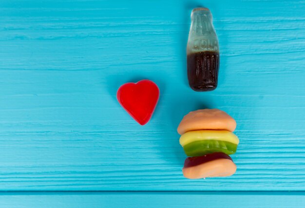 Les bonbons à la gelée représentent sous la forme d'un hamburger et d'une boisson qui est l'amour sur une table en bois turquoise