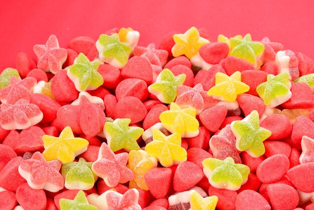 Bonbons gommeux colorés assortis et sucette sur fond rouge. Vue de dessus. Bonbons à la gelée.