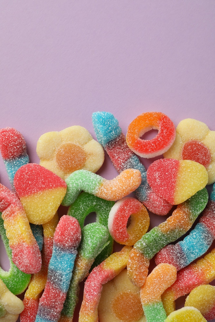 Photo bonbons gommeux sur fond violet, espace pour le texte.