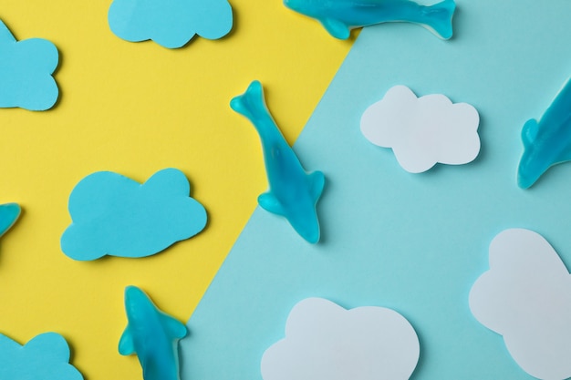 Bonbons gommeux en forme de baleine et nuages décoratifs sur fond bicolore.