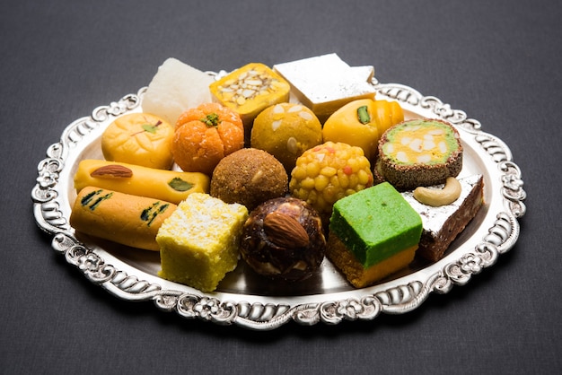 Bonbons indiens servis dans une assiette en argent ou en bois. variété de Peda, burfi, laddu en assiette décorative, mise au point sélective