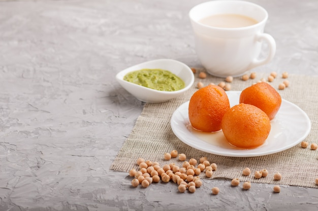 Bonbons indiens traditionnels gulab jamun en plaque blanche avec chutney à la menthe