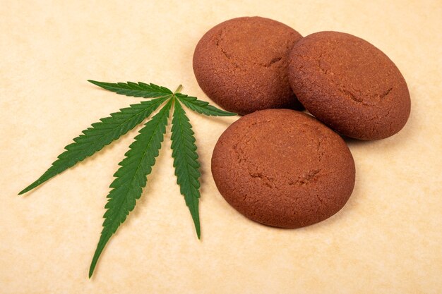 Bonbons à la marijuana, cookie aux pépites de chocolat avec feuille verte de gros plan de plante de cannabis.