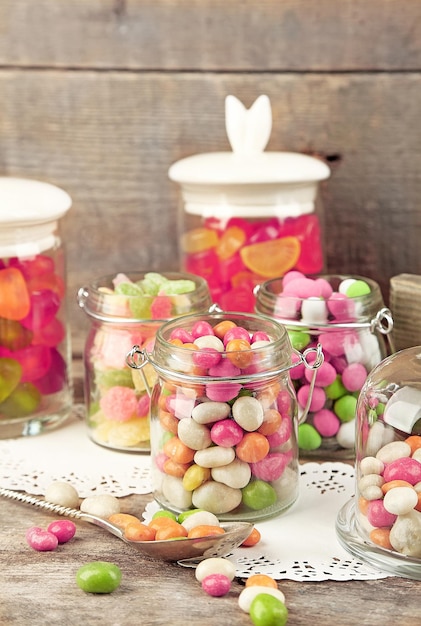 Bonbons multicolores dans des bocaux en verre sur fond de bois