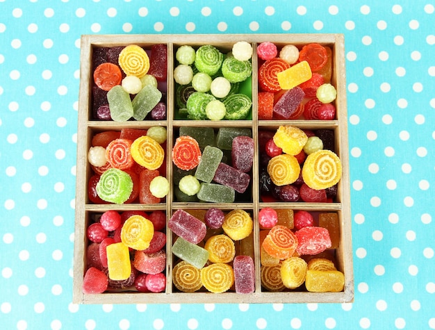 Bonbons multicolores dans une boîte en bois sur fond de couleur