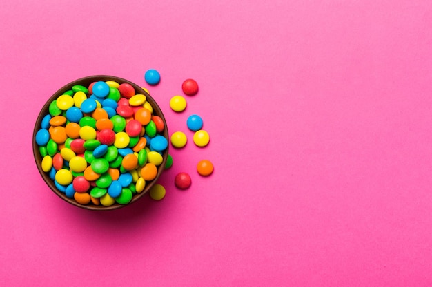 Des bonbons multicolores dans un bol sur un fond coloré concept d'anniversaire et de fête Vue supérieure avec espace de copie