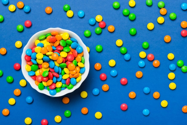 Bonbons multicolores dans un bol sur fond coloré concept d'anniversaire et de vacances Vue de dessus avec espace de copie