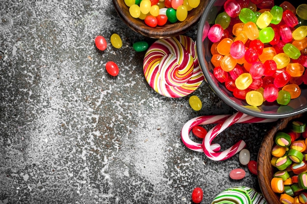 Bonbons multicolores, gelée et guimauves dans un bol. Sur un fond rustique.