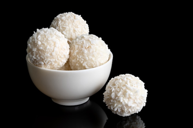 Bonbons à la noix de coco dans une tasse blanche isolée sur fond noir