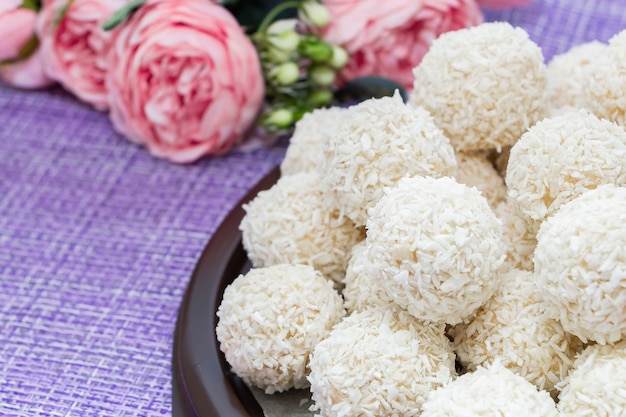 Bonbons à la noix de coco faits maison sur fond de fleurs roses. Bonbons pour la Saint-Valentin.