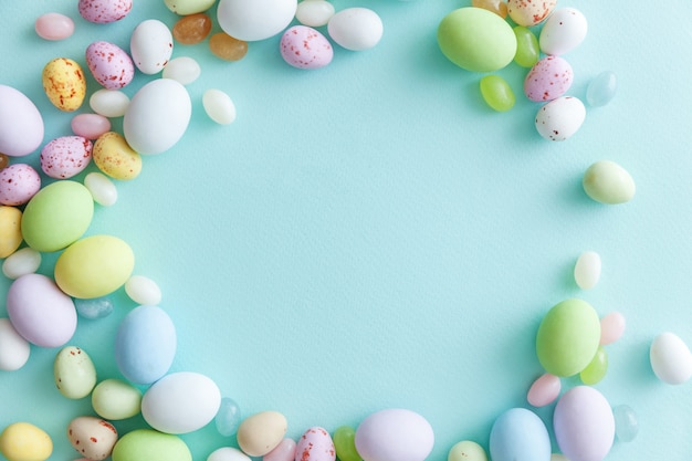 Bonbons de Pâques oeufs en chocolat et bonbons jellybean isolés sur tableau bleu