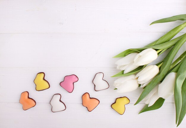 Des bonbons pour fêter Pâques. Tulipes blanches, oeufs au chocolat et lapin de Pâques.