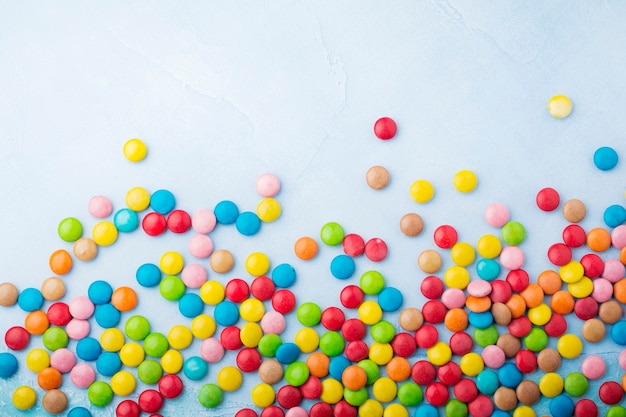 Bonbons ronds au chocolat dans un glaçage au sucre multicolore sur table bleu clair. Mise au point sélective. Vue de dessus. Place pour le texte.