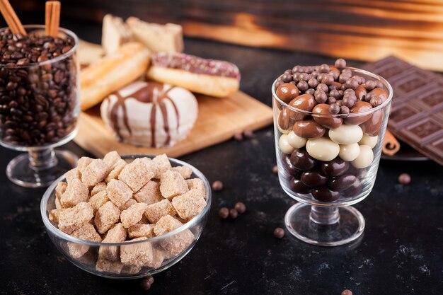 Bonbons, sucre brun, beignets et café sur fond de bois vintage foncé