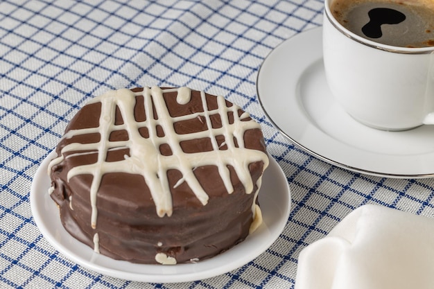 Bonbons typiques d'alfajor au chocolat brun en Argentine avec une tasse de café sur une nappe à carreaux