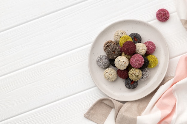 Bonbons végétaliens colorés boules d'énergie sur plaque sur table en bois blanc