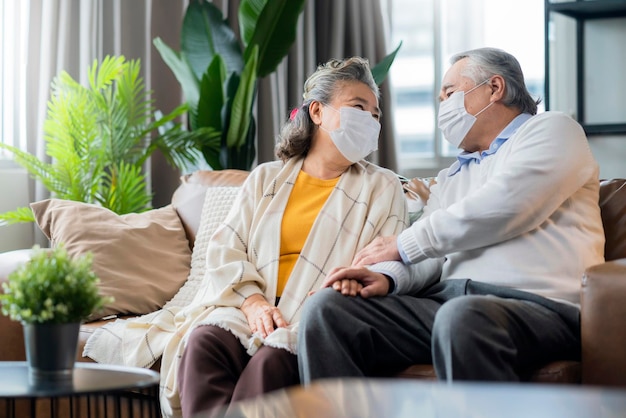 Bonheur couple de personnes âgées asiatiques s'asseoir se détendre conversation du matin sur un canapé dans le salonvieux asiatiques portant un masque assis sur un canapé à la maison concept d'idées d'isolement à la maison