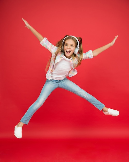 Bonheur d'enfance. enfant heureux écouter de la musique. liberté et réussite. Petite fille aux écouteurs. atteindre son rêve. voler dans les airs. devenir fou. petite fille excitée porte un casque. danse avec sa chanson préférée.