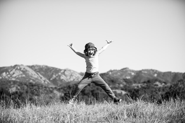 Photo bonheur enfance liberté mouvement et concept de personnes heureux garçon souriant sautant sur la nature