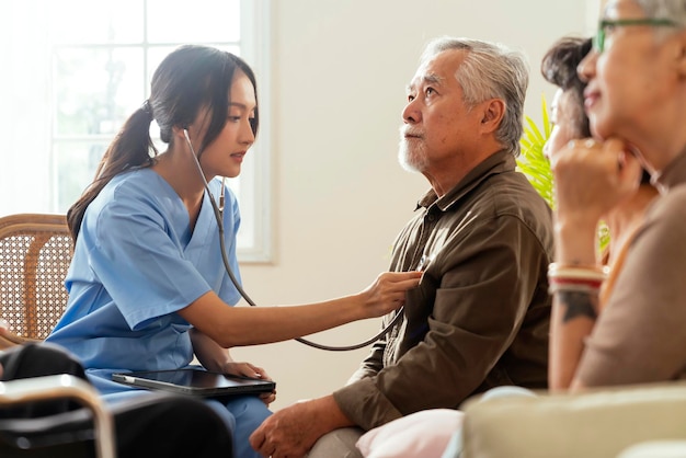 Bonheur Une femme et des hommes âgés joyeux discutant avec une infirmière soignante médecin ayant une consultation de contrôle de santé dans la zone de vieLes gardiens avec un couple de personnes âgées assis dans le salon de la maison de retraite