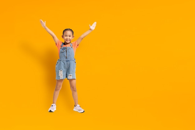 Bonheur de fille enfant asiatique drôle sur fond jaune