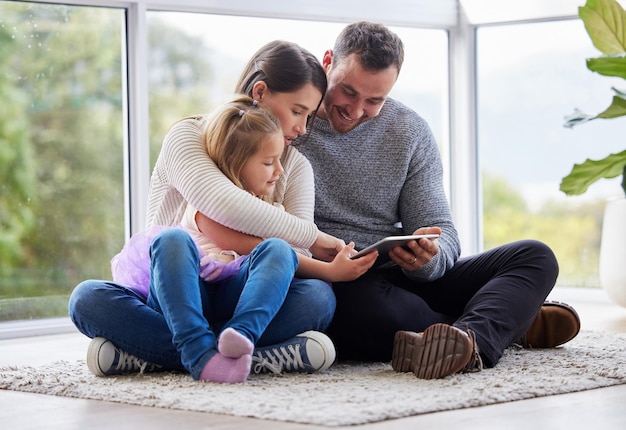 Le bonheur personnifié Photo d'une jeune famille utilisant une tablette numérique à la maison