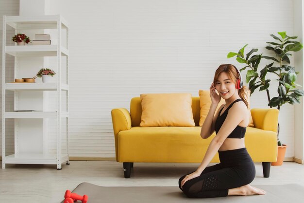 Bonheur de style de vie Fitness à domicile pour femmes asiatiques Asseyez-vous et détendez-vous en écoutant de la musique sur un tapis de yoga