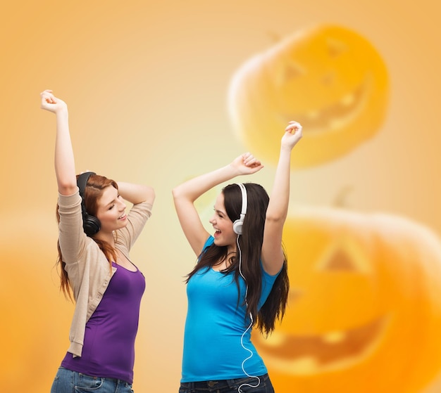 bonheur, vacances, amitié et concept de personnes - adolescentes souriantes étreignant sur fond de citrouilles d'halloween