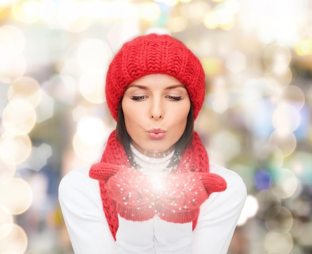 bonheur, vacances d'hiver, noël et concept de personnes - jeune femme souriante au chapeau rouge, écharpe et mitaines sur fond de lumières