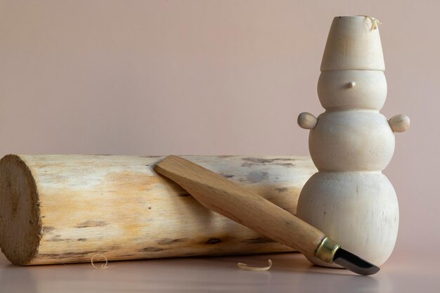 Photo un bonhomme de neige en bois est assis à côté d'un grand morceau de bois.