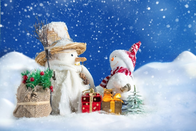 Bonhomme de neige dans une congère avec des cadeaux et des arbres de Noël et attendant le Père Noël. La carte postale concept de Noël et du nouvel an.