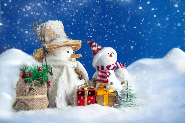 Bonhomme de neige dans une congère avec des cadeaux et des arbres de Noël et attendant le Père Noël. Le concept de carte postale de Noël et du nouvel an.