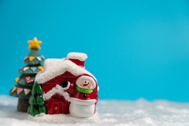 Bonhomme de neige et maison rouge et arbre de Noël sur la neige.