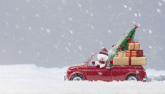 Bonhomme de neige en voiture rouge livrant un sapin de Noël et des cadeaux à fond enneigé.