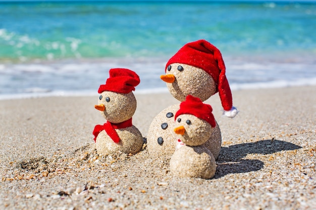 Bonhommes de neige de sable sur la plage en chapeaux