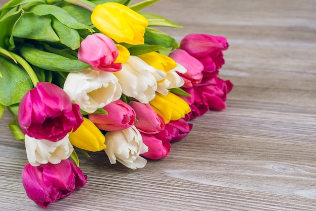 Bonjour le concept de printemps. Photo en gros plan de beau bouquet multicolore de belles tulipes sur l'espace de copie de table en bois gris