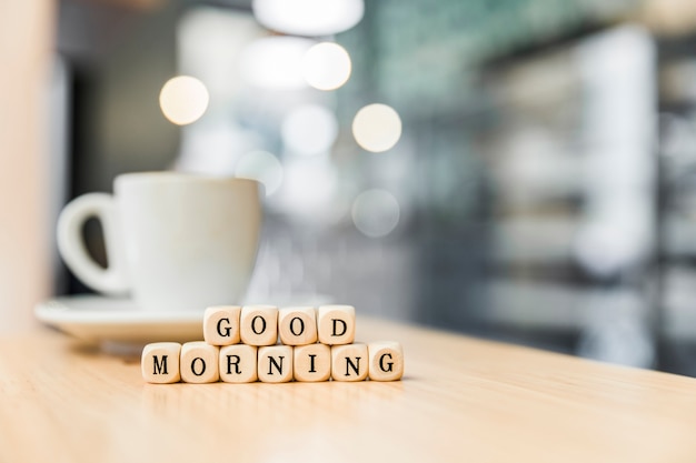 Photo bonjour cubes cubes avec une tasse de café sur le bureau en bois