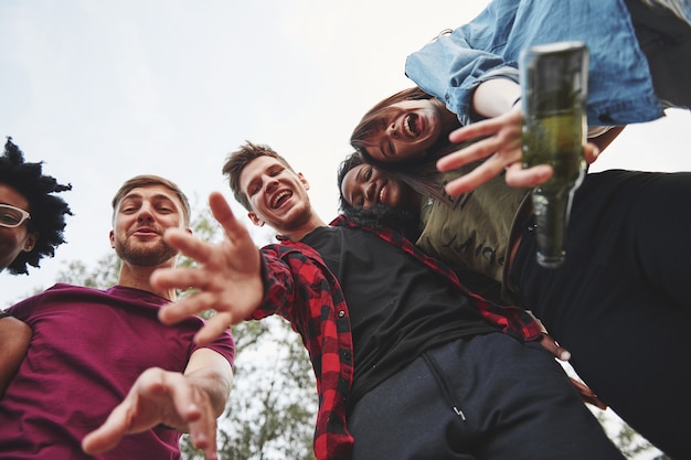 Bonjour. Un groupe multiethnique de personnes fait la fête à l'extérieur. Vue de bas.