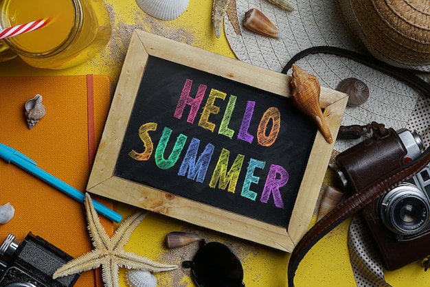 Bonjour texte d'été coloré sur tableau noir entre les accessoires de plage d'été