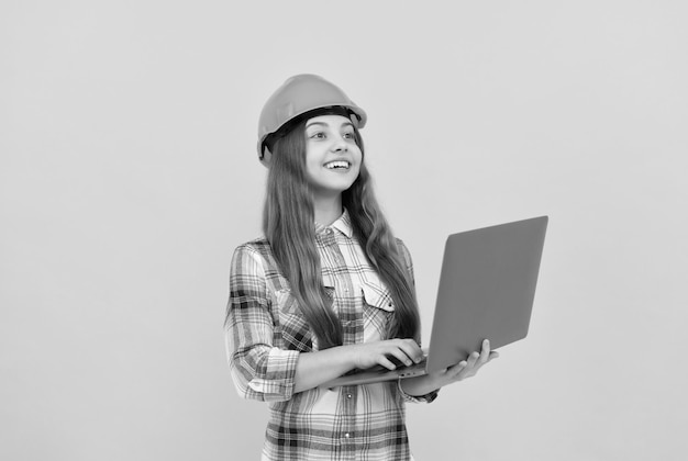 Bonne adolescente en casque et chemise à carreaux à l'aide d'un ordinateur portable