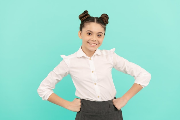 Bonne adolescente de retour à l'école debout avec les bras akimbo fond bleu, adolescent.