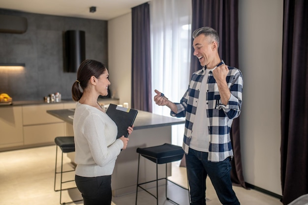 Bonne affaire Heureux homme d'âge moyen regardant les clés en main et souriante femme brune