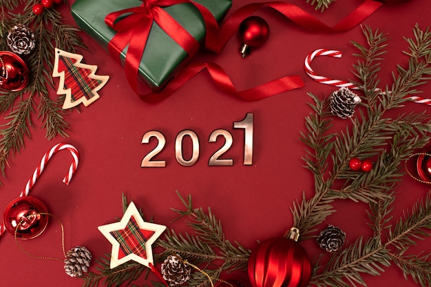 Photo bonne année 2021. les chiffres d'or 2021 avec un chapeau de noël sont sur fond rouge avec des paillettes. décoration de fête de vacances ou concept de carte postale avec vue de dessus et espace de copie.