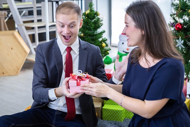 Bonne année 2022, concept, Happy couple holding échangeant des cadeaux et Offrir un cadeau à la fête de Noël et du Nouvel An Fond d'arbre de Noël Après avoir terminé le travail commercial